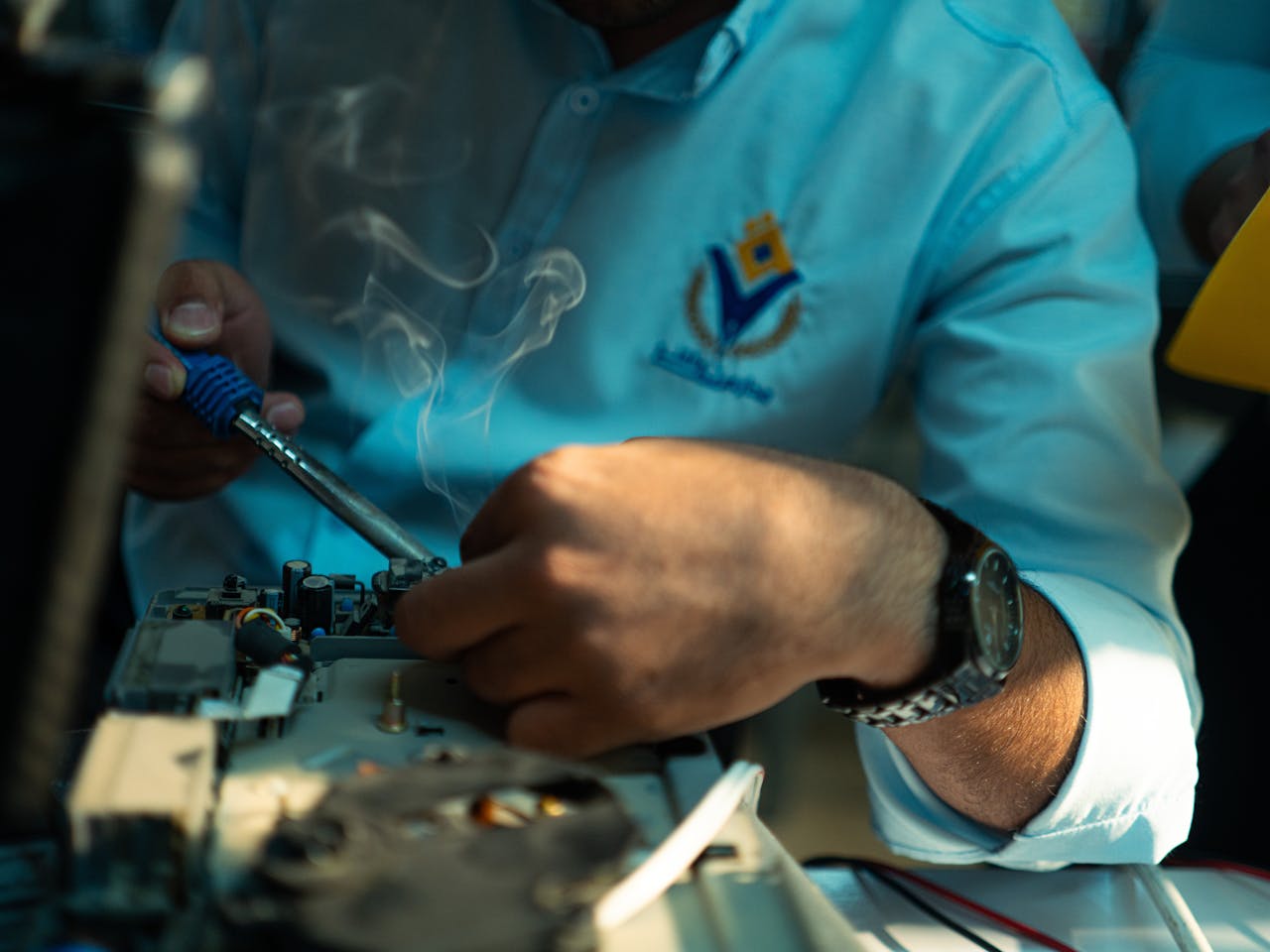contact-img Technician focused on soldering electronics, showcasing precision and skill in technology repair.