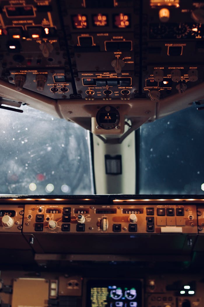services-03 Close-up view of an aircraft cockpit's illuminated controls and instruments at night.