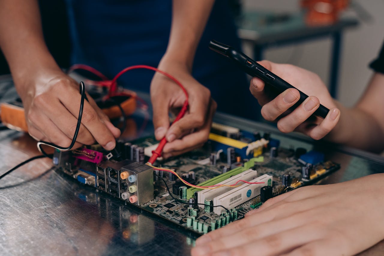 why-choose-me Close-up of hands working on a motherboard using electrical tools and tester.